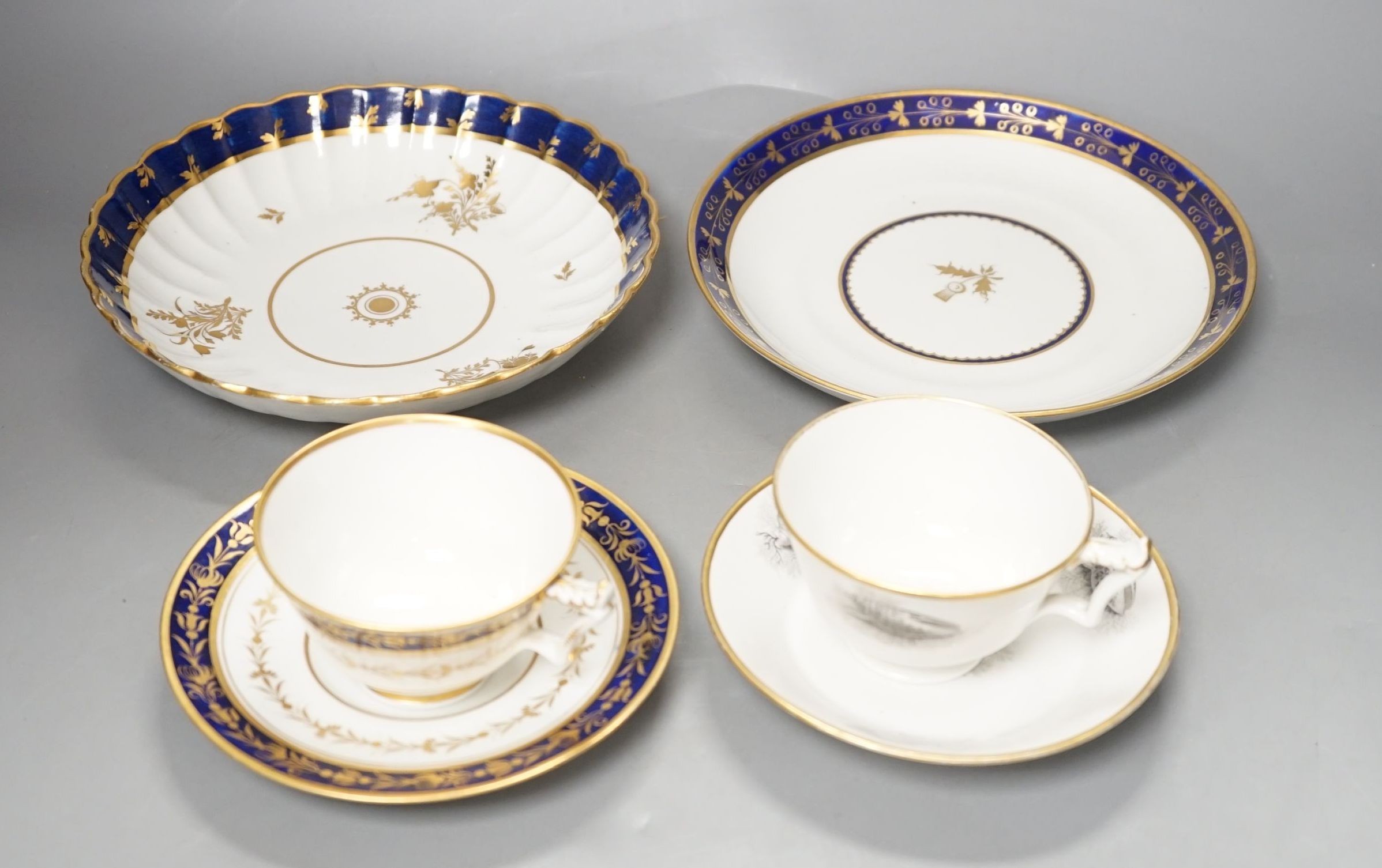 A Flight Barr and Barr teacup and saucer printed with shells, similar teacup and saucer with blue and gold decoration, and two Flight Barr and Barr gold and blue saucers dishes c. 1820, dish 20 cms diameter.